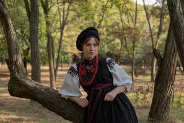 А woman in Ukrainian national embroidered dress vyshyvanka, outdoors in the forest.