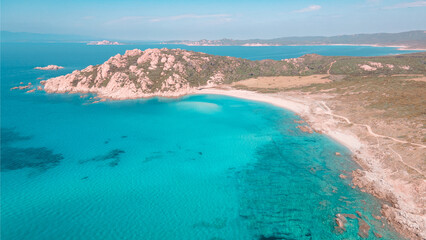 Aerial view from the drone of the Monti Russu promontory in Aglientu in Northern Sardinia, the emerald blue sea contrasts with the pink granite promontory and the surrounding Mediterranean scrub. 