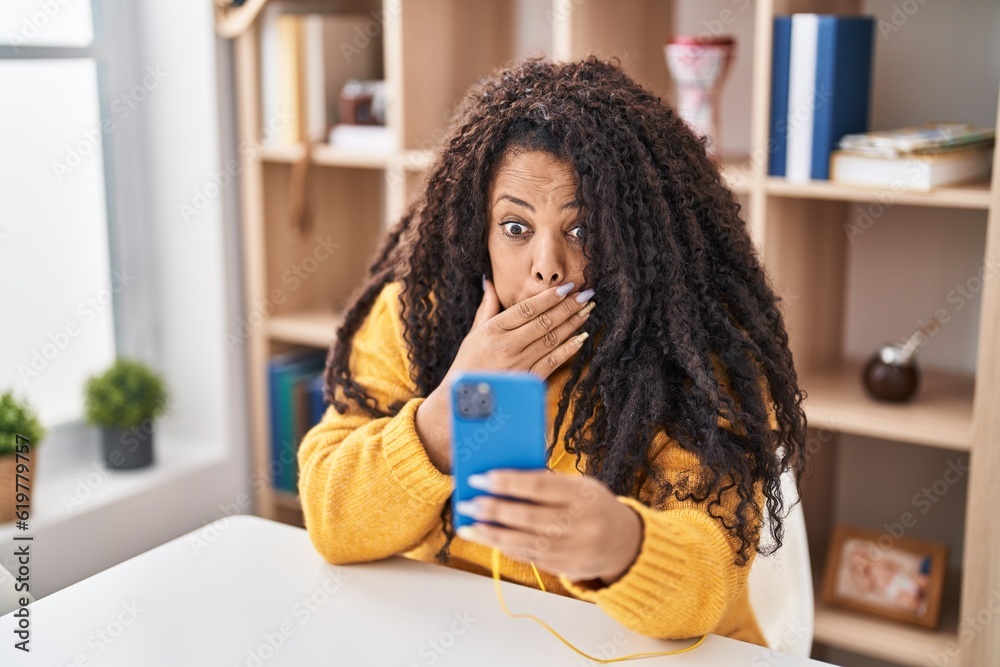 Sticker Plus size hispanic woman using smartphone sitting on the table covering mouth with hand, shocked and afraid for mistake. surprised expression