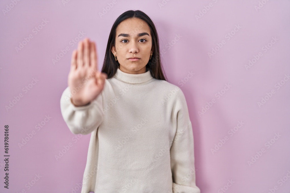 Wall mural Young south asian woman standing over pink background doing stop sing with palm of the hand. warning expression with negative and serious gesture on the face. - Wall murals