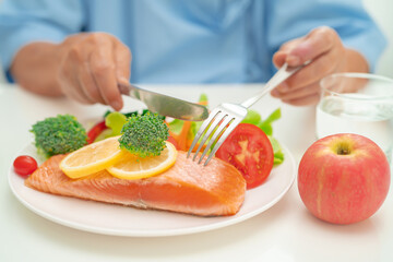 Asian elderly woman patient eating salmon steak breakfast with vegetable healthy food in hospital.
