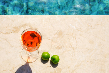 Glass of pink wine and yellow sunglasses at the pool.