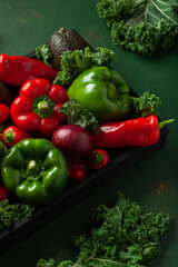 assorted red and green vegetables tomatoes, bell peppers, kale avocado