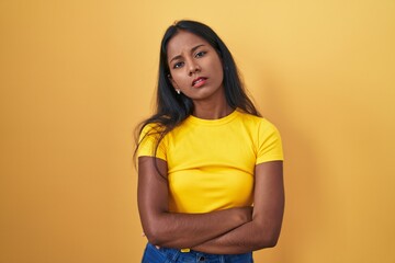 Young indian woman standing over yellow background looking sleepy and tired, exhausted for fatigue and hangover, lazy eyes in the morning.