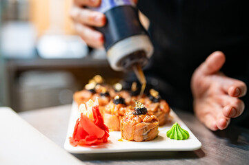 professional chef's hands making sushi roll in a restaurant kitchen