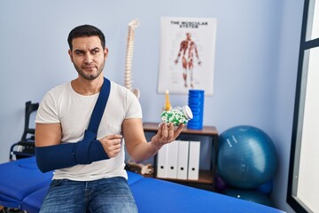 Young hispanic man injured physiotherapy patient holding pills at rehab clinic