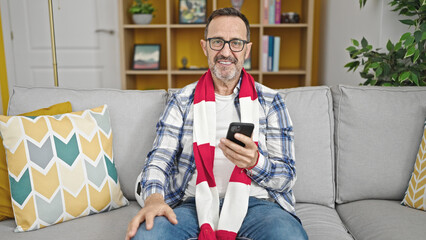 Obraz premium Middle age man supporting soccer team using smartphone at home