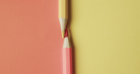 Close up of red and yellow pencil crayons on red and yellow background with copy space