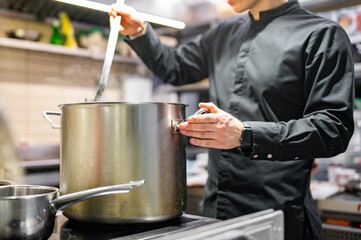 Fototapeta na wymiar man chef cooking soup on restaurant kitchen