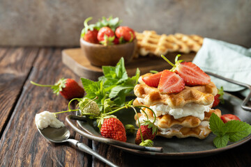 Homemade Belgian waffles with fresh berrie strawberries and ricotta cheese for breakfast on a rustic table. Copy space.
