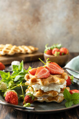 Belgian waffles with fresh berrie strawberries and ricotta cheese for breakfast on a rustic table. Copy space.
