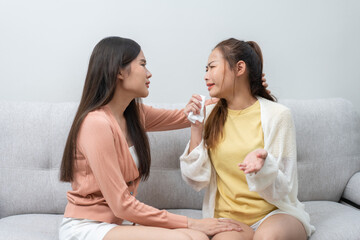 Obraz na płótnie Canvas Two women talking about problems at home. Asian women embrace to calm their sad best friends from feeling down. Female friends supporting each other. Problems, friendship, and care concept