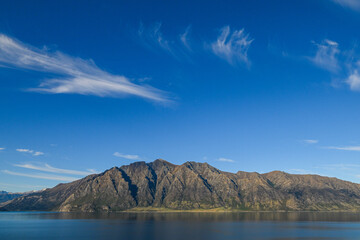 A view of mountains behind Lake Pukaki in Glentanner, Canterbury, New Zealand on a sunny afternoon. 