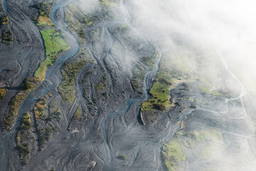 An aerial view through clouds of Glacier water from Mount Cook flowing through the Waiho River in...
