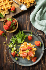 Belgian waffles with fresh berrie strawberries and ricotta cheese for breakfast on a rustic table. View from above.
