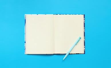 Mockup of an open notepad with a pen on a blue background. Top view, flat lay. Diary for entries, copy space