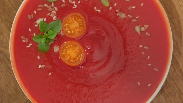 Tomato soup puree gazpacho on table close-up top view rotate.