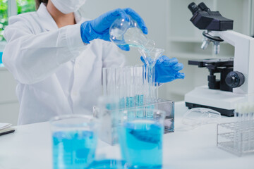 Fototapeta premium Close up of Female scientist or researcher is pouring blue substance or liquid in to a sample test tube. Concept of science, biochemistry, chemical, biotechnology laboratory. Analyzing and experiment