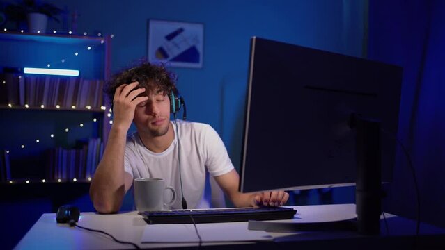 Tired student gamer near computer sleeps. Young man sleep while playing computer games.