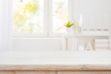 Wood desk in front of blurred bookshelf and window background