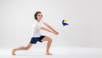 Fototapeta na wymiar A young volleyball player is training with a ball on a white background. Action, sport, health, team, fitness concept