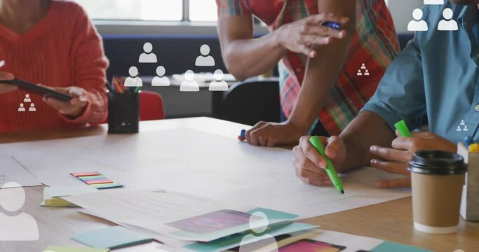 Animation of profile icons floating over mid section of colleagues discussing over a plan at office