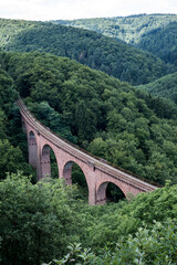 old arch Bridge railway viaduct between hills in the green Forest Germany trees