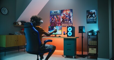 African American teenager in VR headset plays virtual third-person 3D shooter on personal computer using wireless controllers. Video game online streaming or cybersport championship. Gaming at home. © Framestock
