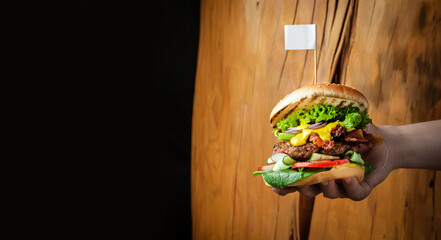 hands holding Homemade burger with juicy meat cutlet, vegetables, sauce. Long banner format