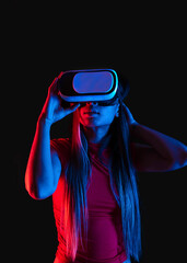 unrecognizable chinese woman wearing VR head set on black background with red and blue light from a side
