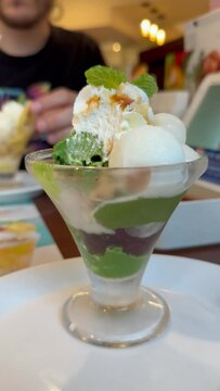 Latin tourist eating matcha, anko and mochi parfait, an iconic dessert in Japanese cuisine, at a restaurant in Japan.
