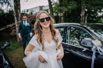 Fototapeta na wymiar A happy bride wearing sunglasses walks ahead of the grooms