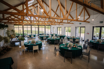 The venue is decorated for a wedding with round tables and green tablecloths, it looks unique and...