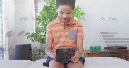 Animation of graphs and currency signs over biracial boy using digital tablet while sitting on sofa - Powered by Adobe