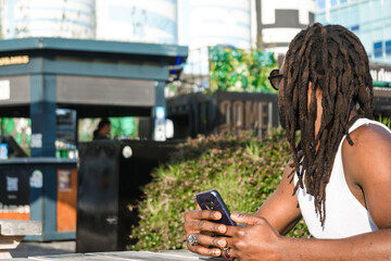 man with dreadlocks sitting outdoors turns to see the restaurant to be served