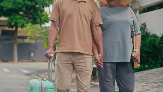 Cropped image of senior couple walking with suitcase waiting for transport to airport