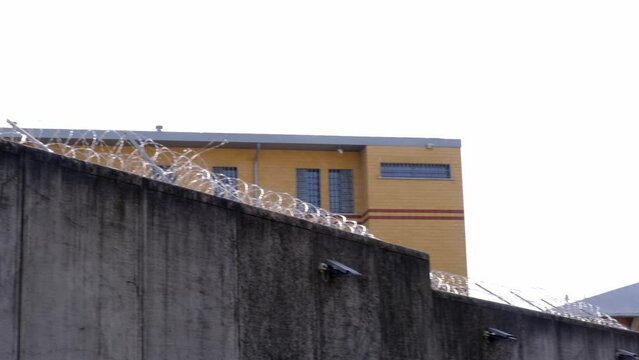 many rows of barbedwire, high concrete fence, barbed wire fence on top, building for execution of punishments for criminals, concept prison, security zone, symbol of bondage, hopelessness of captivity