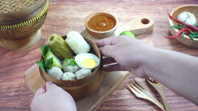 Fish cake dumplings or Siomay is a traditional food from Indonesia made of potato egg cabbage roll peanut chili lime served in a bamboo bowl