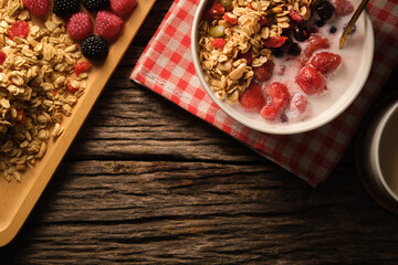 Crunchy oat granola with fresh milk and berries in bowl on wooden background. Healthy breakfast, vegan, dieting and weight loss concept.