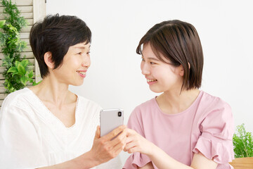 自宅でスマホを使う母親と娘