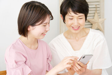 自宅でスマホを使う母親と娘
