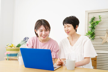 自宅でノートパソコンを使う母親と娘