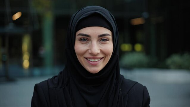 Portrait of successful beautiful executive businesswoman looking at camera and smile, standing near modern office workplace. Young Asia muslim female lady posing for business headshot outdoor.