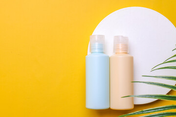 Pastel color of cosmetic bottles on white podium with natural palm leaves. The blank label for mock up. 