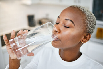 Healthy, glass and woman drinking water for thirst, wellness and liquid nutrition at her home. Calm, energy and African female person enjoying cold health drink in the kitchen of her apartment.