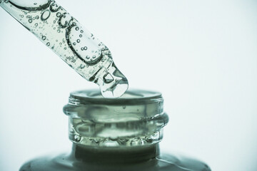 Glass pipette with cosmetic and frosted glass bottle on a white background. Side view, macro.