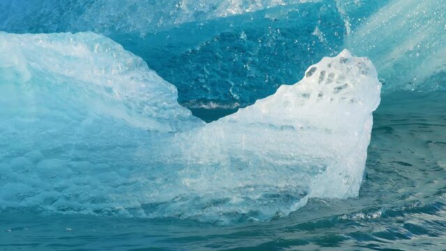 Pure blue ice in arctic. Icebergs breakaway from glacier in Iceland. Crystal clear blue ice floats in salt turquoise water.