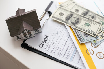 House model put on bank note and loan agreement document. Real estate concept.