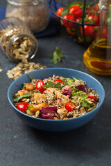 Salad with quinoa, avocado and chicken. Front view. Served in a blue bowl.