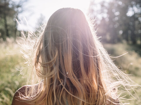 Back view of the young female with beautiful blond straight long hairs in motion